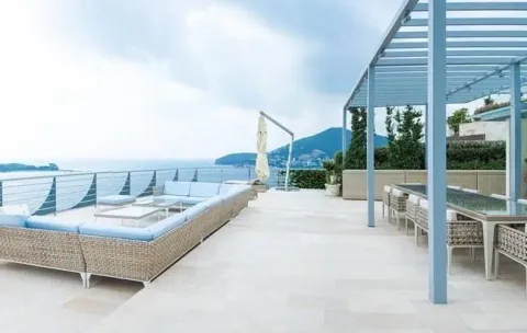 Spacious rooftop terrace with seating furniture, dining table, and sea view. - image 8