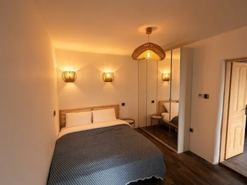 Moderna spavaća soba sa bračnim krevetom, garderoberom sa ogledalima i toplom rasvjetom. - image 4