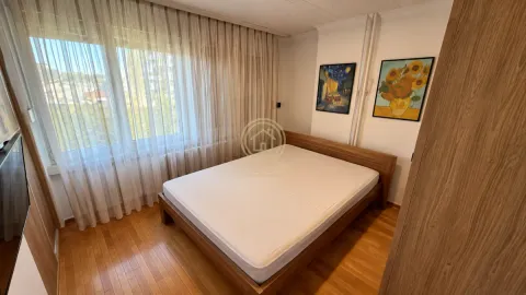 Nameštena spavaća soba sa bračnim krevetom, drvenim podom i prozorom prekrivenim zavesama. - image 6