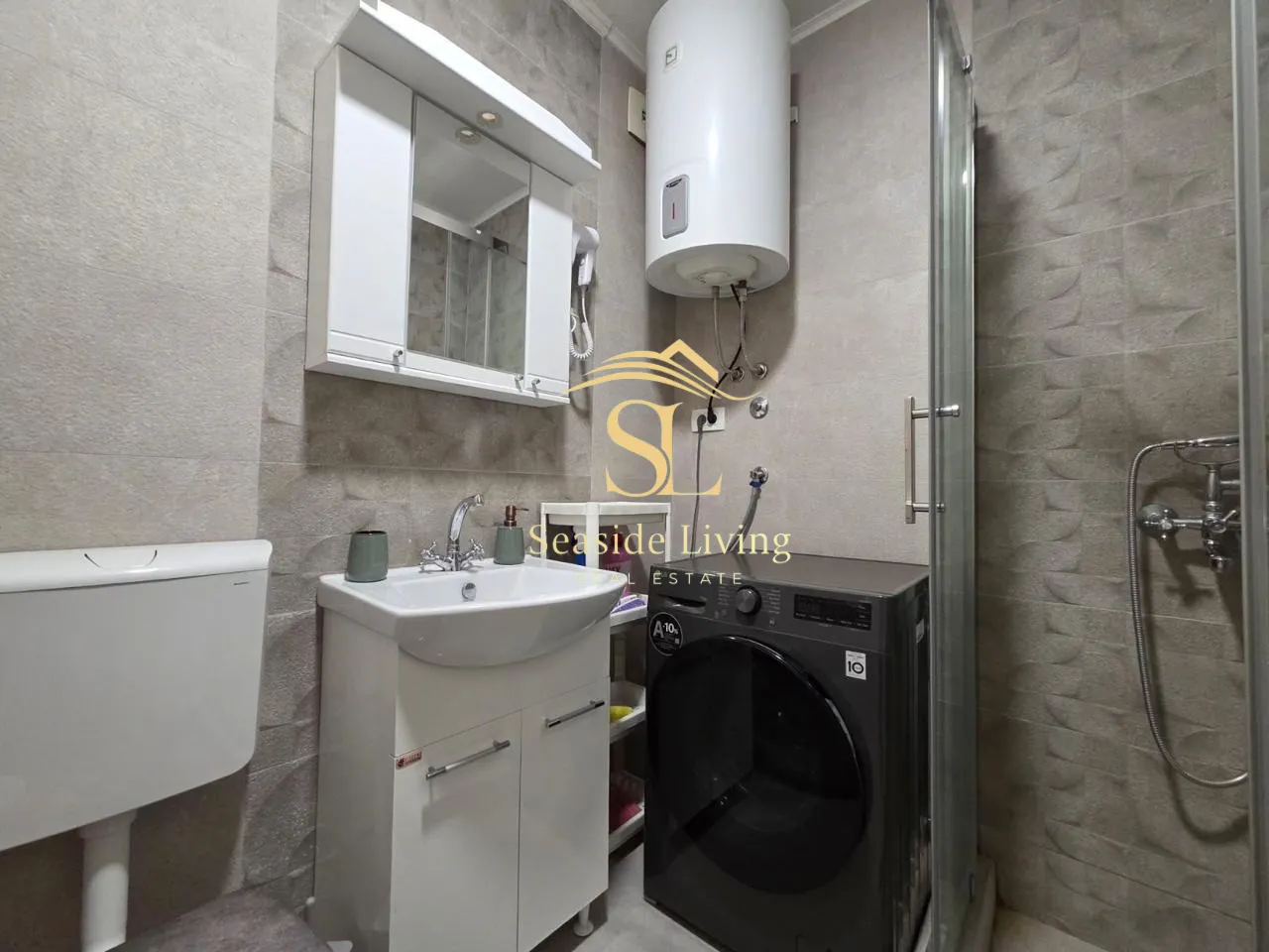 Smaller bathroom with a sink, shower cabin, water heater, and washing machine.