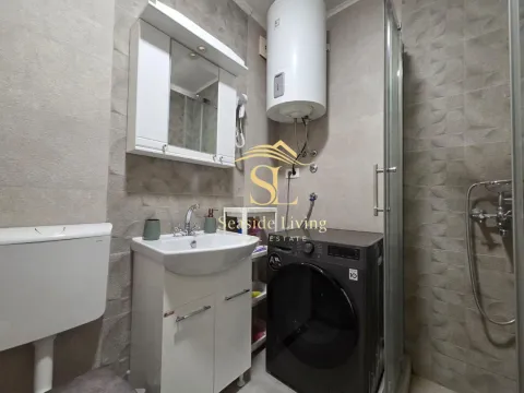 Smaller bathroom with a sink, shower cabin, water heater, and washing machine. - image 11