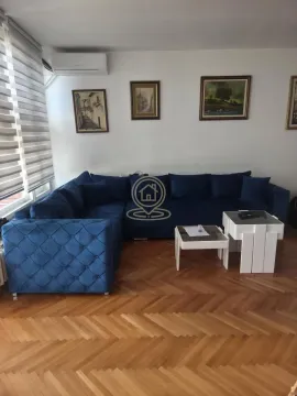 Living room with a large blue sectional sofa and parquet flooring. - image 2