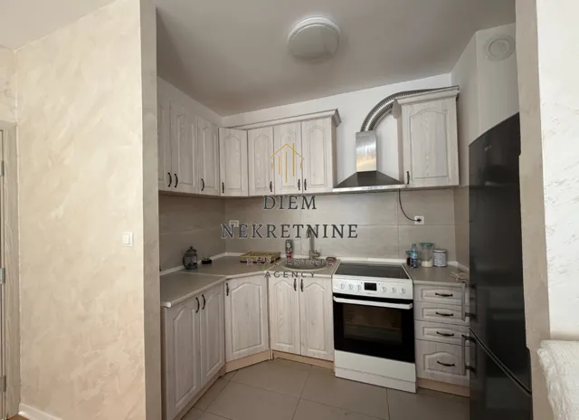 Kitchen equipped with light wooden cabinets and white appliances.