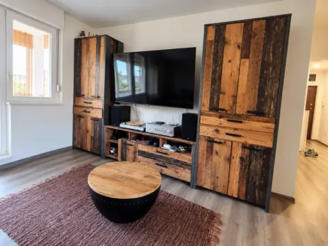 Living room with a TV, wooden furniture, and a round coffee table. - image 4