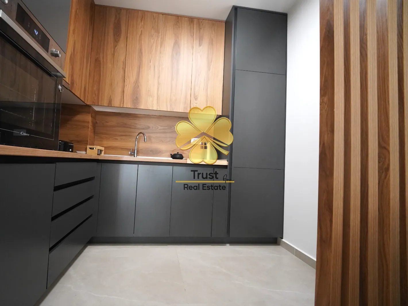 Modern kitchen with wood elements and dark cabinets.