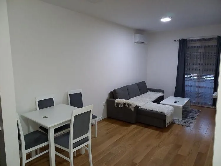 Svijetla dnevna soba sa ugaonom garniturom i trpezarijskim stolom sa stolicama.