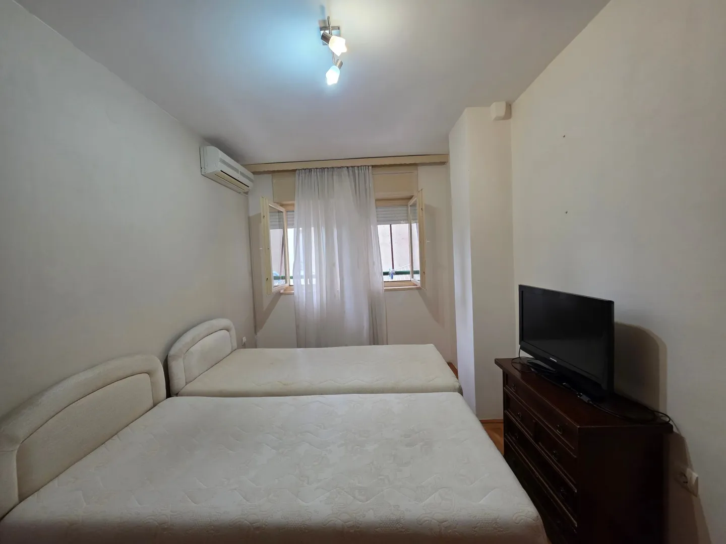 Bedroom with two beds and a television.