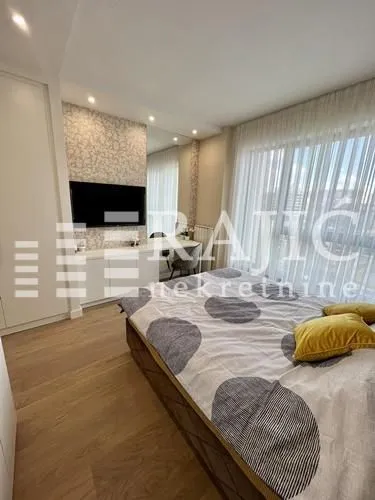 Modern bedroom with a double bed, built-in wardrobe, and large window.