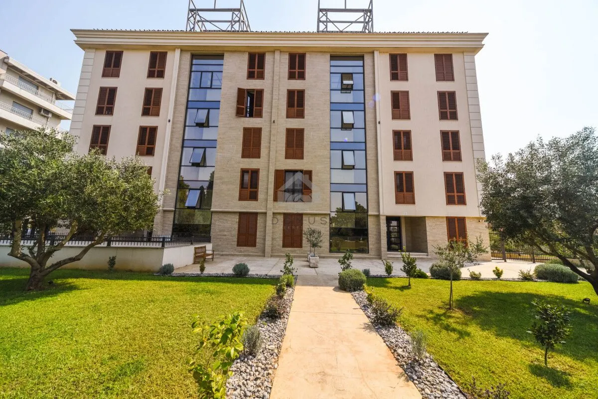 Prednji dio stambene zgrade sa uređenim dvorištem i zelenilom.