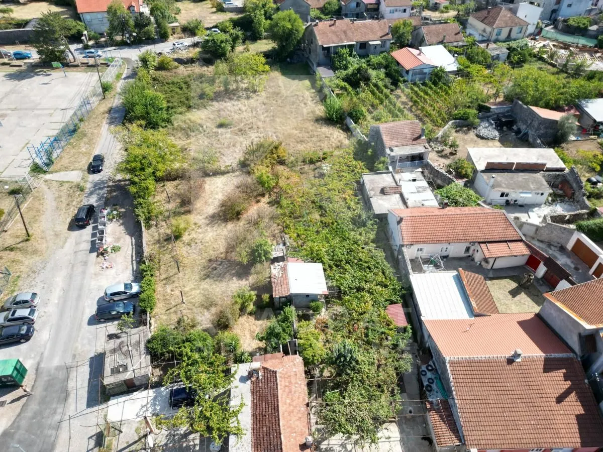 Pogled iz vazduha na plac sa okolnim objektima i putem.