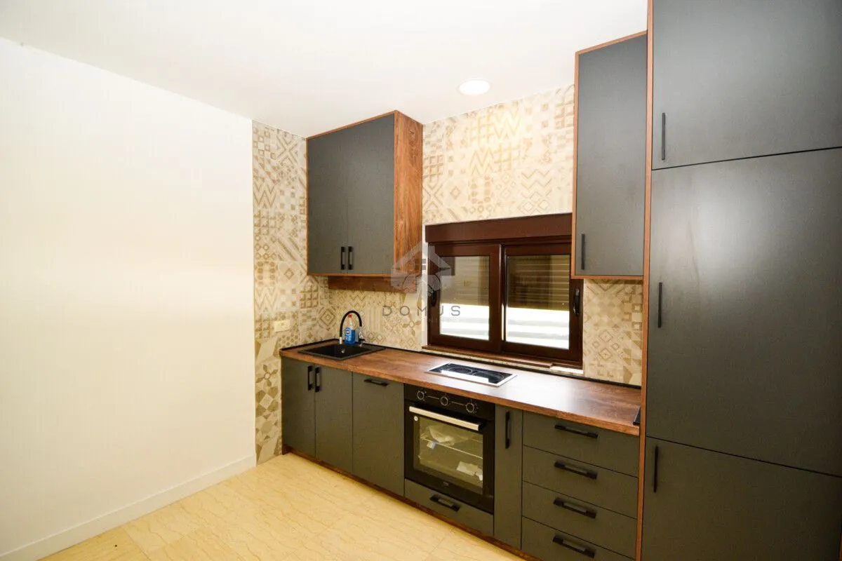 Modern kitchen with dark cabinets and a wooden countertop.