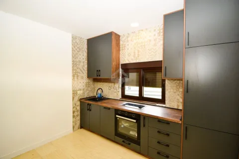 Modern kitchen with dark cabinets and a wooden countertop. - image 13