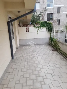 Paved courtyard in front of the building with a fence and greenery. - image 7