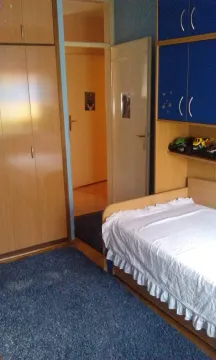 A simple bedroom with a single bed and wooden wardrobes. - image 9