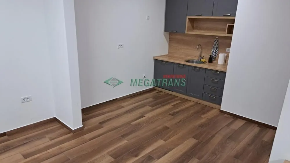 Manja kuhinja sa sivim elementima i drvenim radnim delom.
