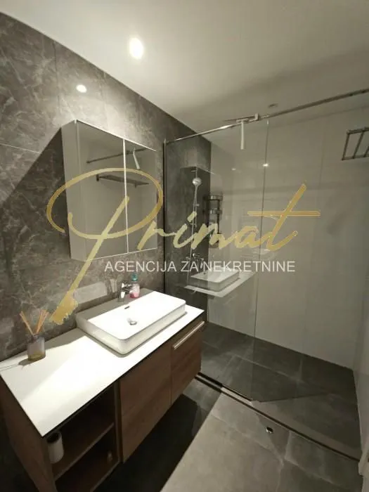 Modernly equipped bathroom with a washbasin and a walk-in shower.