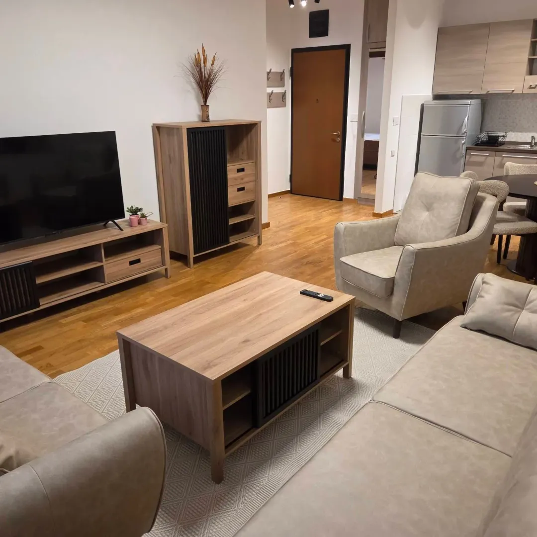 Living room with sofa set, TV and a view of the kitchen.