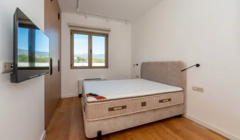 Furnished bedroom with a double bed, wardrobe, and wall-mounted TV. - image 6