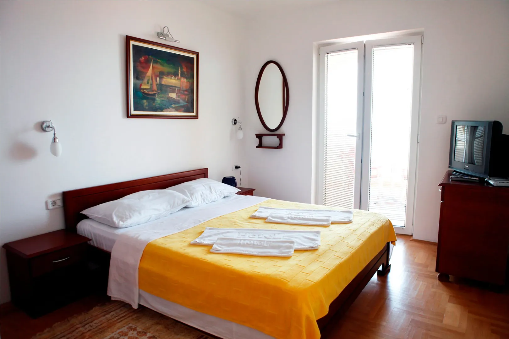 Bright bedroom with a double bed, dresser, and access to the terrace.