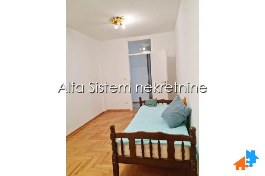 Smaller bedroom with a bed and parquet flooring.