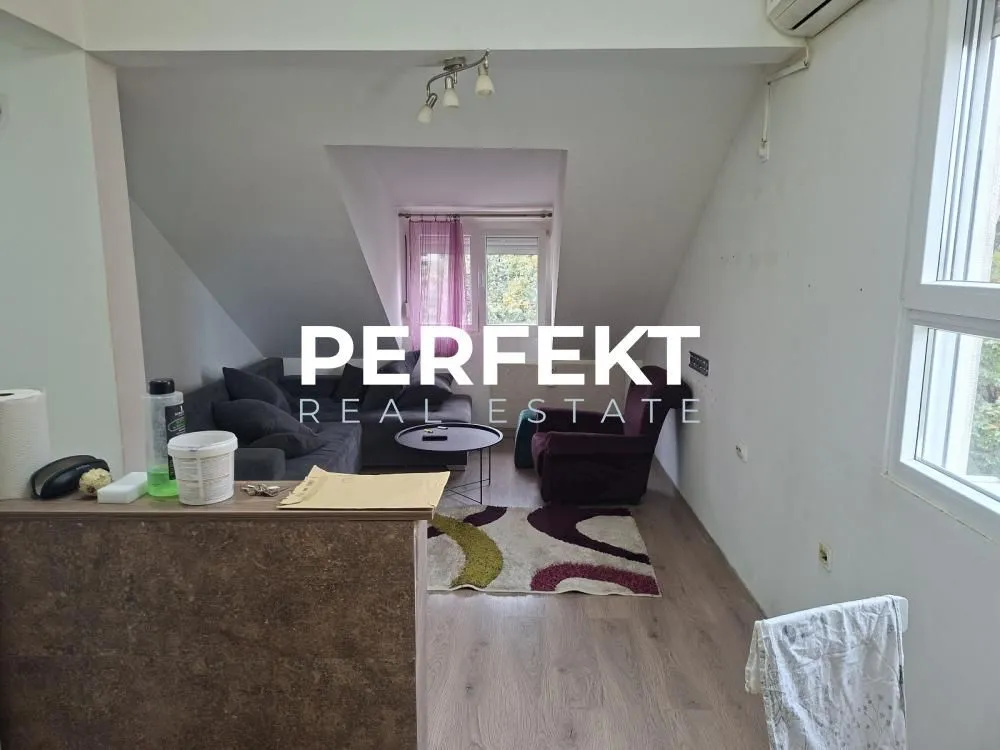 Dnevni boravak sa garniturom i prozorom u potkrovlju.