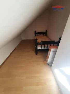 Manja spavaća soba pod kosinom sa krevetom i drvenim podom. - image 10