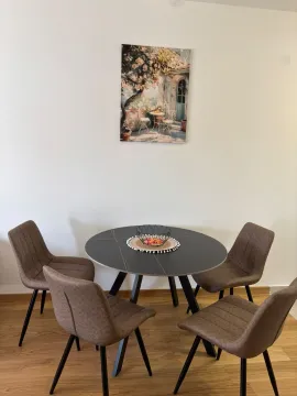 Round dining table with four upholstered chairs and a painting on the wall. - image 2