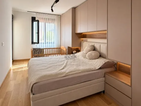 Modern bedroom with a double bed, built-in wardrobes, and a baby cot by the window. - image 8