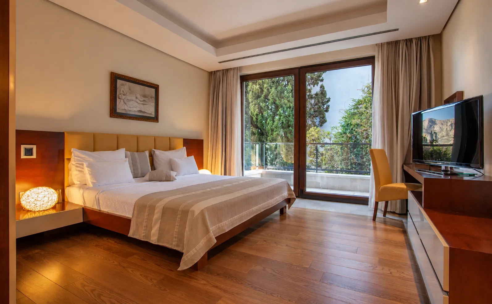 Spacious bedroom with a double bed, wooden flooring, and access to the terrace.