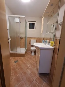 A tidy bathroom equipped with a shower cabin, sink, and toilet. - image 15