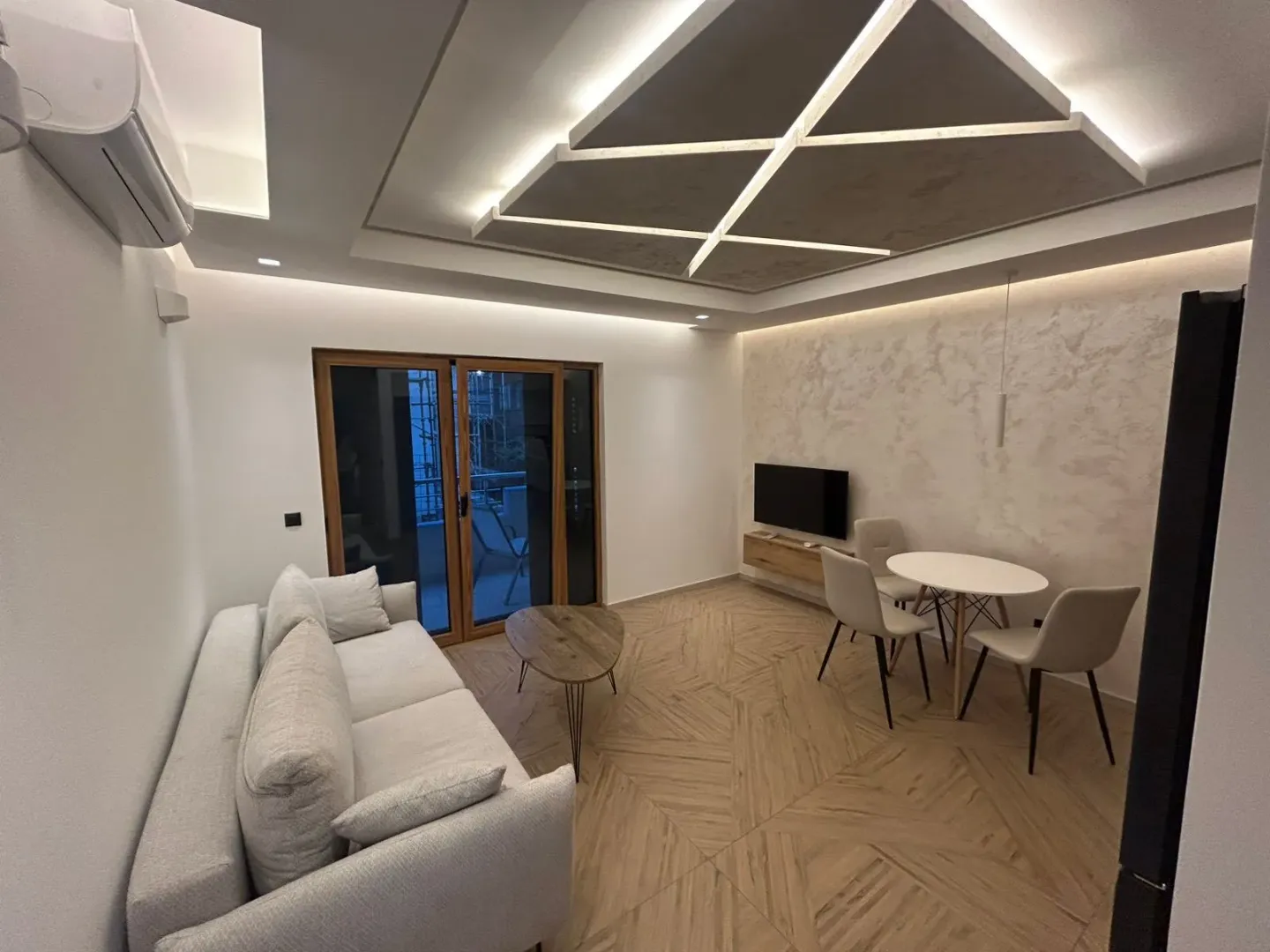 Dnevna soba sa garniturom, trpezarijskim stolom i modernim spuštenim plafonom.
