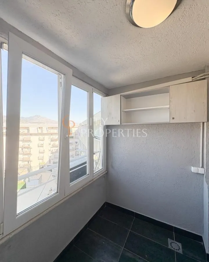 Zastakljeni balkon sa bijelim prozorima i elementima za odlaganje.