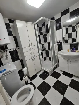 Potpuno opremljeno kupatilo sa tuš kabinom i crno-bijelim pločicama. - image 9
