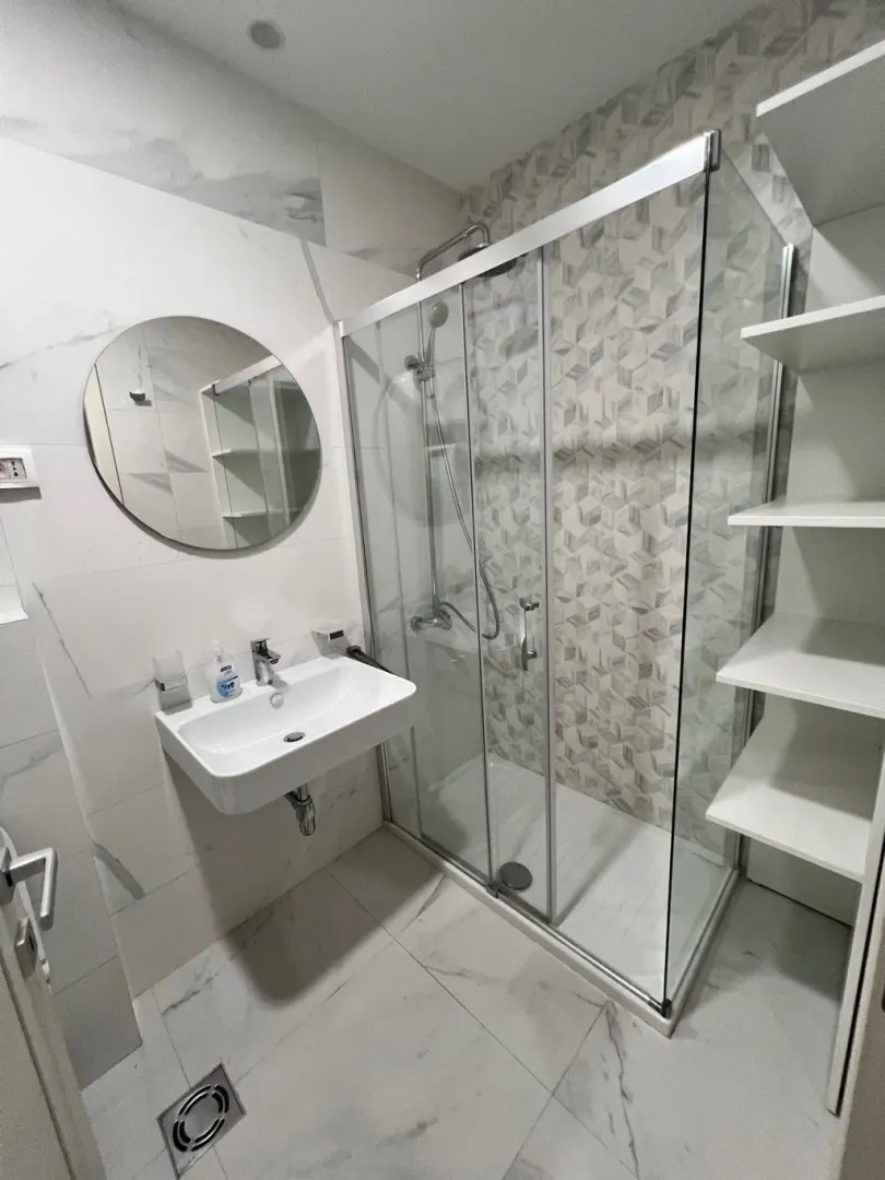 Modern bathroom with a walk-in shower, washbasin, and mirror.