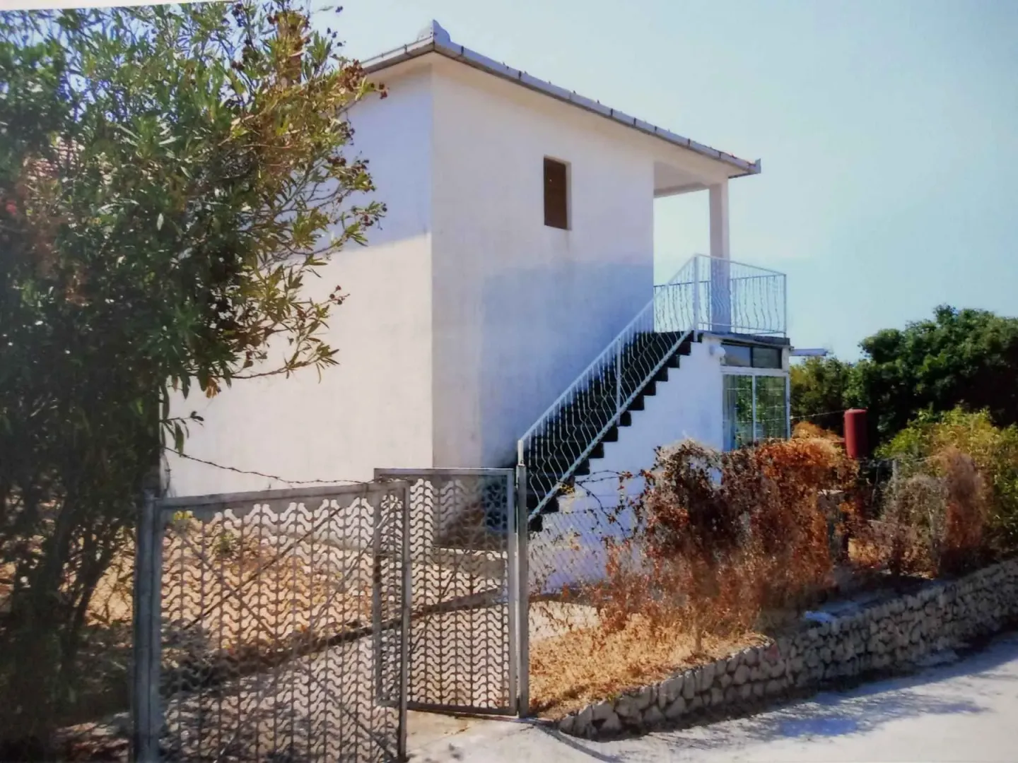 Spoljašnji izgled kuće sa dvorištem i spoljnim stepeništem.