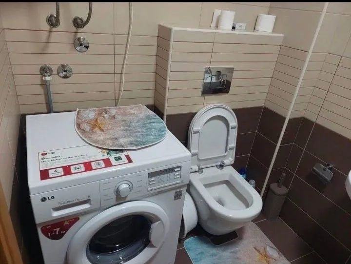 Manje kupatilo sa WC šoljom i veš mašinom.