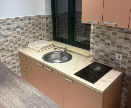 Small kitchen with a sink, built-in cooktop, and beige cabinetry. - image 7