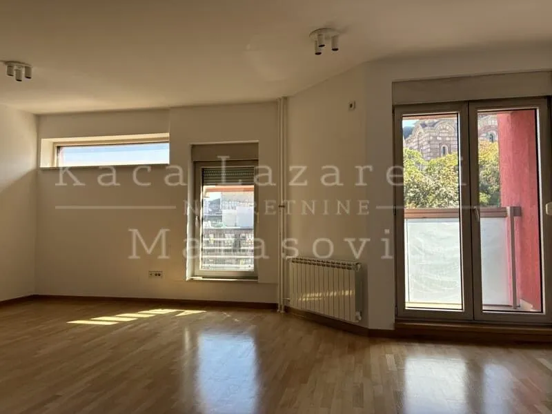 Empty room with parquet flooring and several windows.