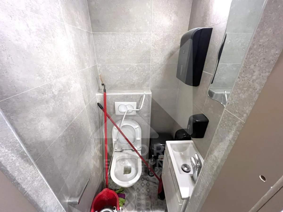 Small bathroom with a toilet, washbasin, and grey tiles.