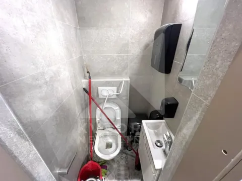 Small bathroom with a toilet, washbasin, and grey tiles. - image 2