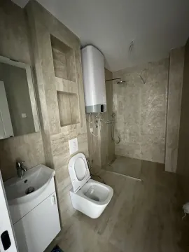 Modern bathroom with a walk-in shower, toilet, and water heater. - image 4
