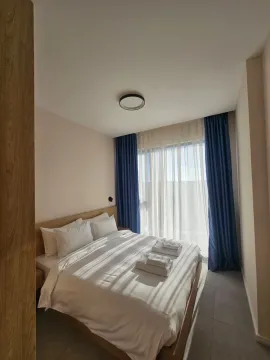Svijetla spavaća soba sa bračnim krevetom i plavim zavjesama. - image 15