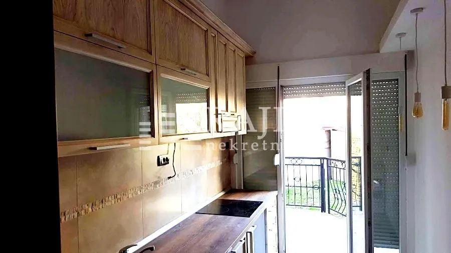 Small kitchen with wooden cabinetry and access to the terrace.