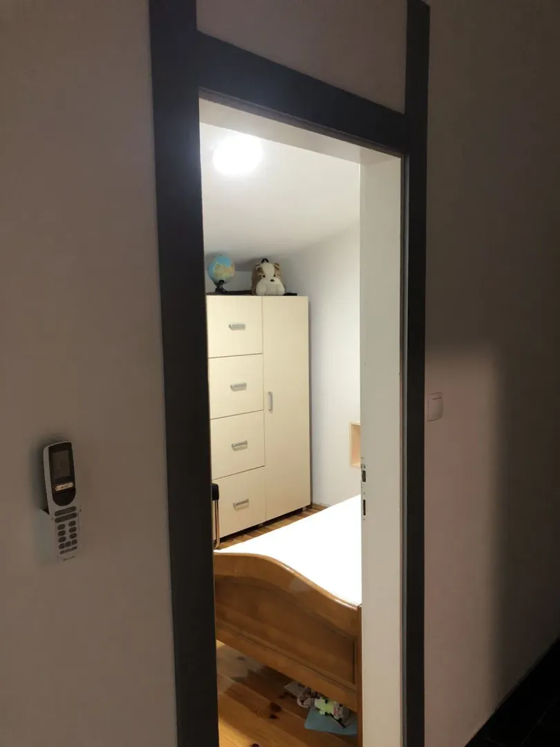 View through a doorway of a bedroom with a wardrobe and a bed.