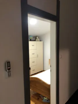 View through a doorway of a bedroom with a wardrobe and a bed. - image 13