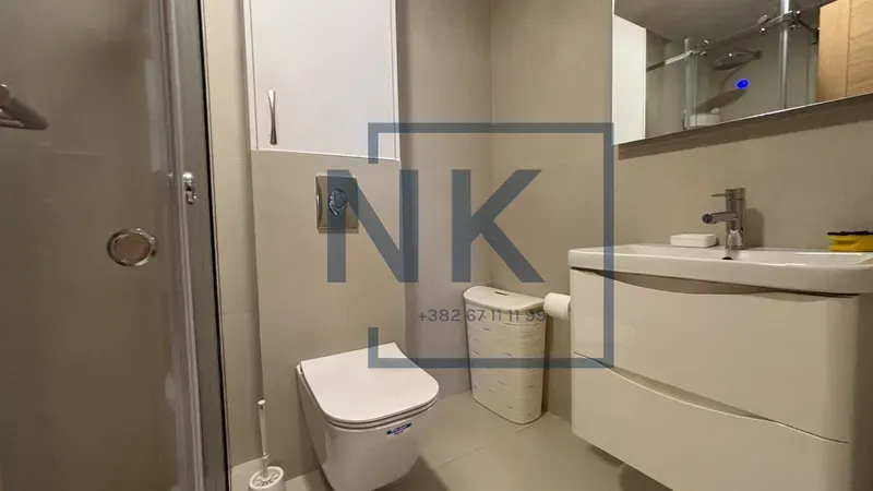 Modern bathroom equipped with a shower cabin, sink, and toilet.