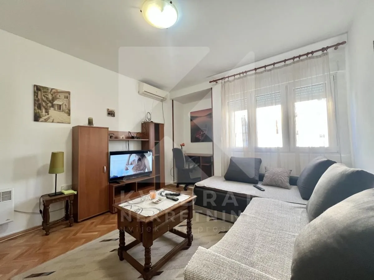 Furnished living room with a sofa, television and a small work corner.