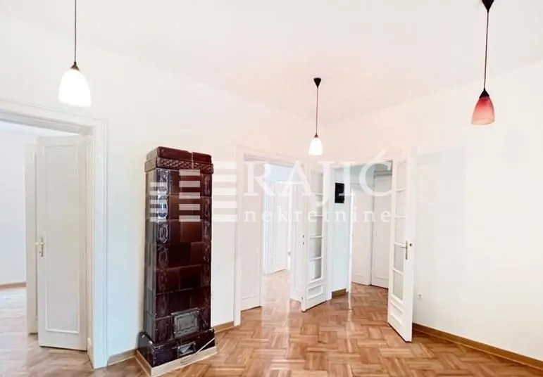 Spacious room with parquet flooring and a traditional wood-burning stove.