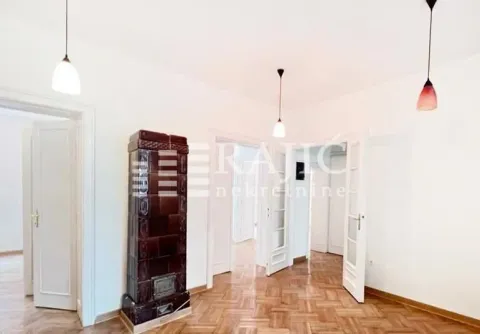 Spacious room with parquet flooring and a traditional wood-burning stove. - image 19