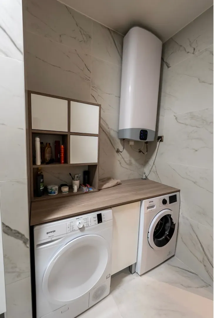 Bathroom equipped with a washing machine, tumble dryer, wall cabinet, and water heater.